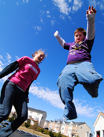 photo of a student and child jumping on a trampoline