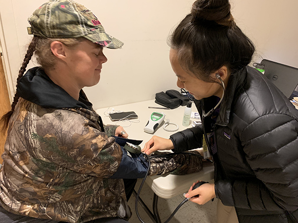 a student volunteer checks a woman's blood pressure